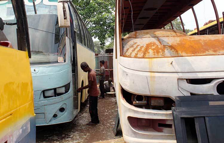 বাসে ঘষা-মাজার কাজ করছে দুই কর্মচারী। ছবি: বিপ্লব দিক্ষিৎ