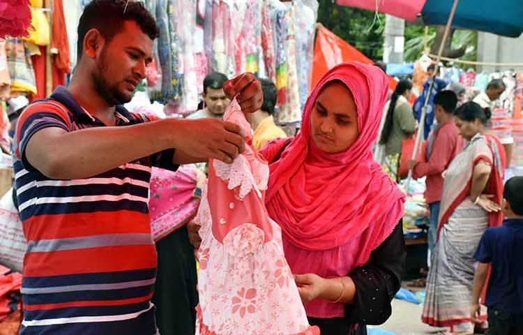 সন্তানের জন্য পোশাক পছন্দ করছেন এক দম্পতি। ছবি: বিপ্লব দিক্ষিৎ