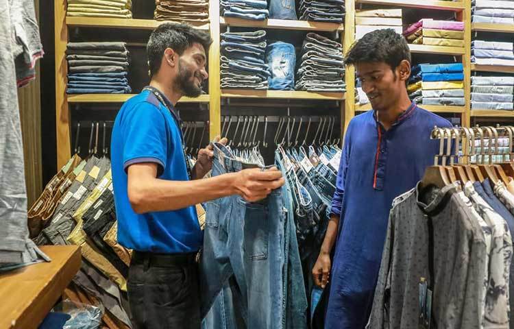 ক্রেতাকে জিন্সের প্যান্ট দেখাচ্ছেন এক দোকানি। ছবি: মাহবুব আলম