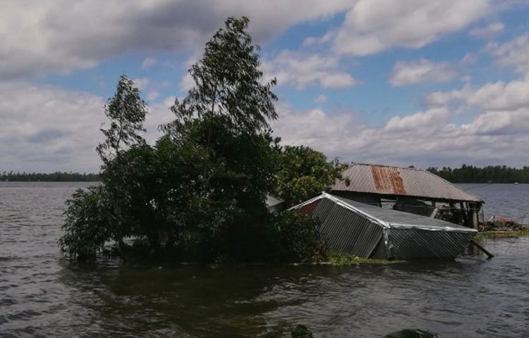 বানের জলে ডুবে যাওয়া বাড়িটি দেখে মনে হচ্ছে এটি নদীর মাঝে। ছবি: মাহবুব আলম