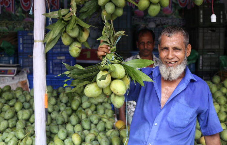 আম দেখাচ্ছেন এক স্টলকর্মী। ছবি: মাহবুব আলম