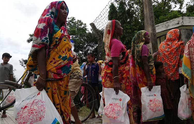 ত্রাণ নিয়ে যাচ্ছেন নারীরা। ছবি: মাহবুব আলম