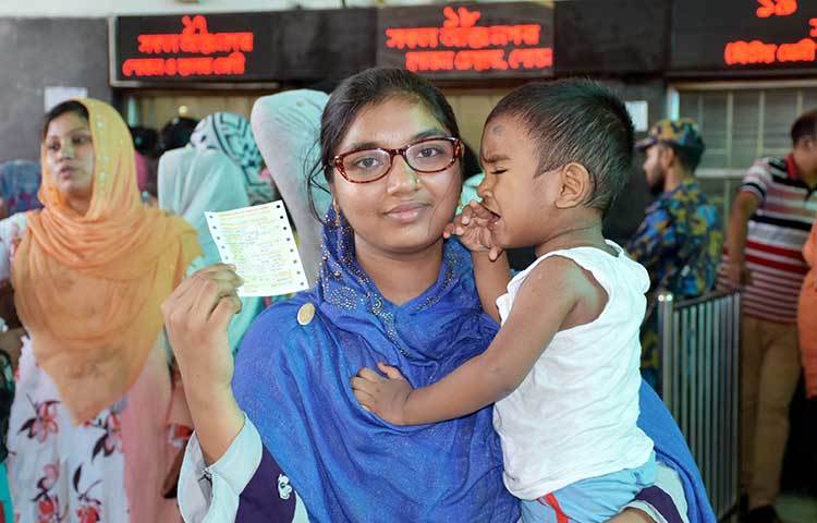 শিশু সন্তানকে নিয়ে টিকিট কাটতে এসেছিলেন এই নারী।  ছবি: বিপ্লব দিক্ষিৎ