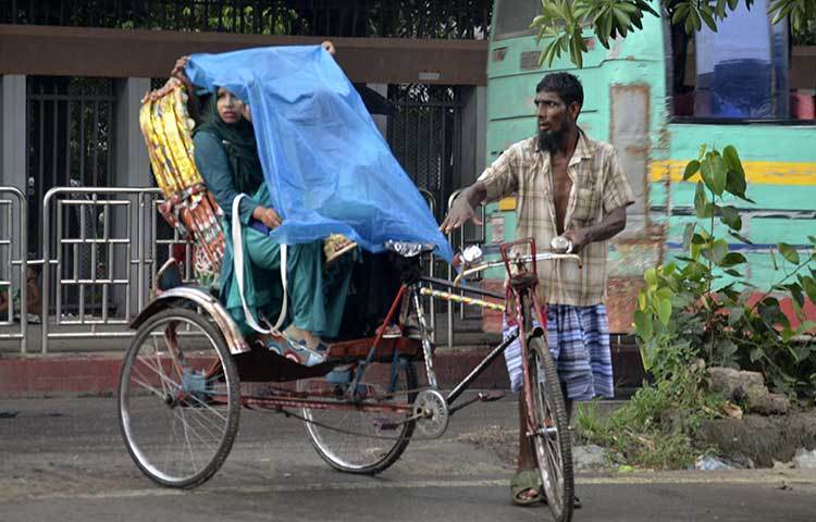 বৃষ্টি থেকে বাঁচতে এই রিকশার যাত্রী পলিথিন ব্যবহার করেছেন। ছবি: বিপ্লব দিক্ষিৎ