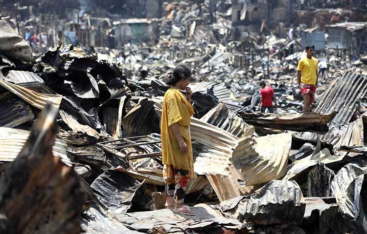 পুড়ে যাওয়া স্তূপ থেকে কিভাবে সাজাবে আবার সংসার সেই ভাবনায় এই নারী। ছবি: বিপ্লব দিক্ষিৎ