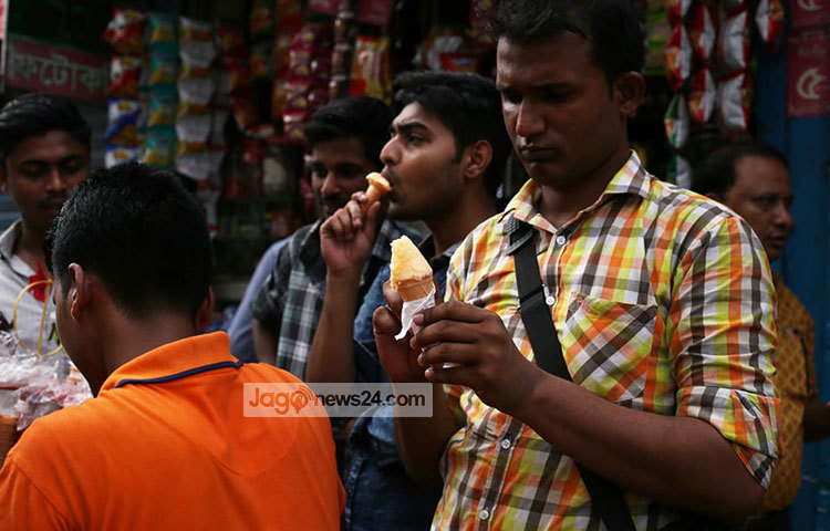 গরমে পিপাসা মেটাতে কেউ কেউ আইসক্রিম কিনে খাচ্ছেন। ছবি: মাহবুব আলম