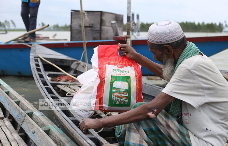 ত্রাণ নিয়ে বাড়ি ফিরছেন এক বৃদ্ধ। ছবি: মাহবুব আলম