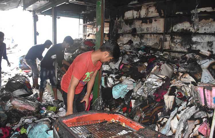 পুড়ে যাওয়া মালপত্র সরাতে ব্যস্ত দোকানের কর্মীরা। ছবি: বিপ্লব দিক্ষিৎ