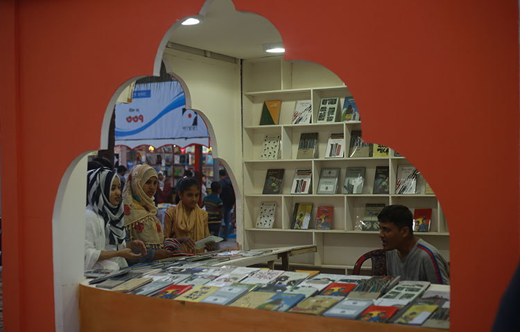 স্টল কর্মীর সঙ্গে কথা বলছেন মেলায় নতুন বই কিনতে আসা পাঠকরা। ছবি: মাহবুব আলম