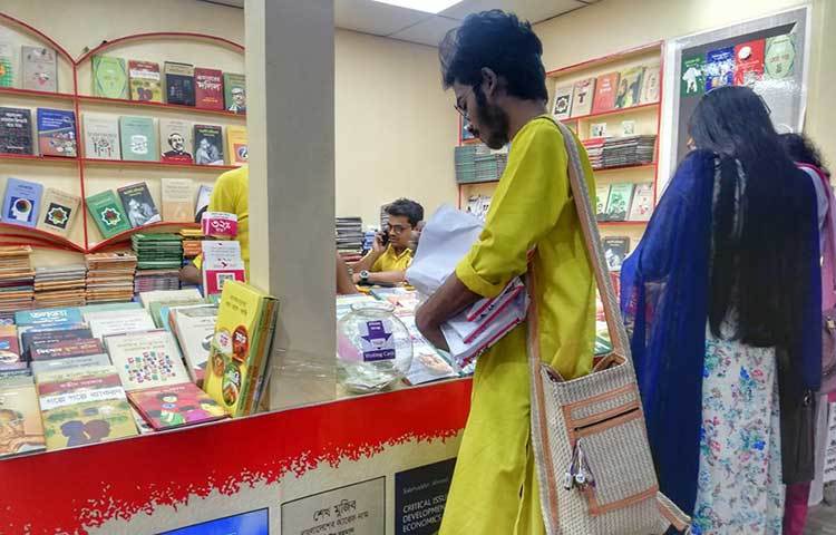 বইমেলায় ঘুরে ঘুরে পছন্দের বই কিনছেন এক পাঠক। ছবি: মাহবুব আলম