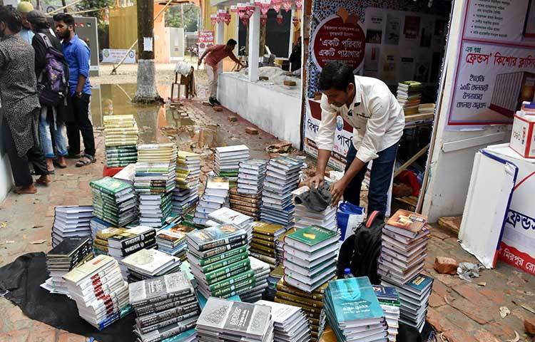 বৃষ্টিতে স্টল ক্ষতিগ্রস্ত হওয়ায় বই বের করে পুনরায় স্টল সাজানো হচ্ছে। ছবি: বিপ্লব দিক্ষিৎ