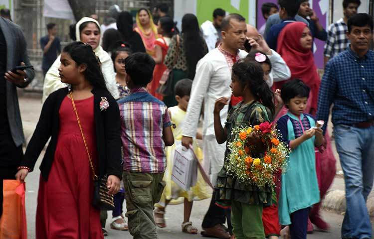 বইমেলায় ফুলের তৈরি মেয়েদের মাথার বেণি বিক্রি করছে এক পথশিশু। ছবি: বিপ্লব দিক্ষিৎ