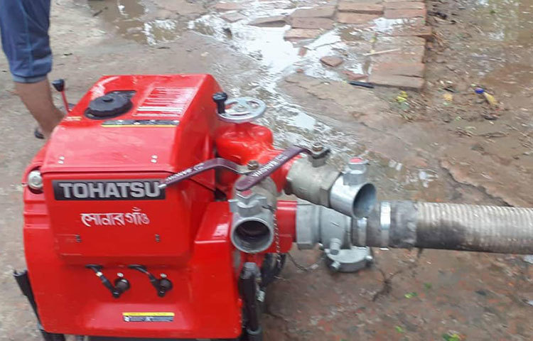 পাম্প দিয়ে ফায়ার সার্ভিসের কর্মীরা বইমেলার মাঠে জমে যাওয়া পানি সেচ দেয়।