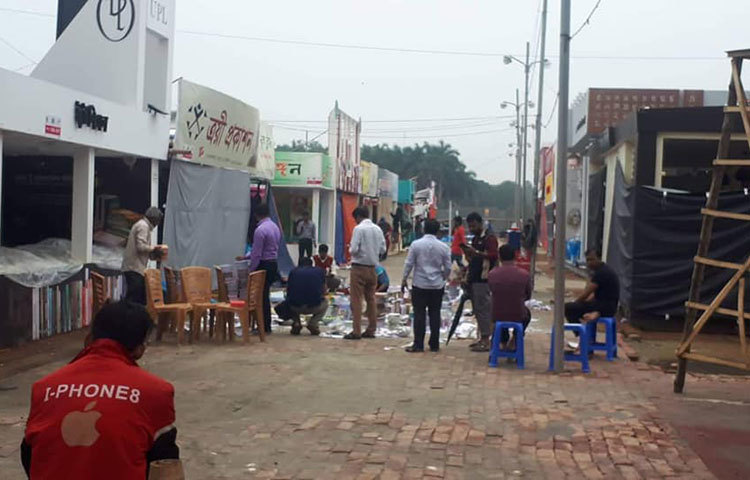 স্টলের মালিকরা বৃষ্টিতে ভিজে যাওয়া স্টলের বইপত্র সরানোর কাজ করছেন।