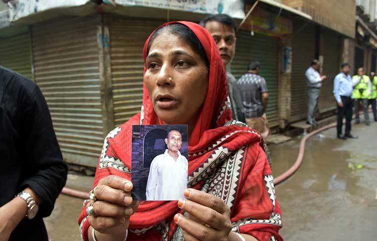 অগ্নিকাণ্ডে হারানো স্বজনের ছবি সাংবাদিকদের দেখাচ্ছেন এক নারী। ছবি: বিপ্লব দিক্ষিৎ