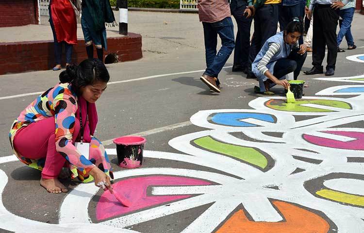 কেন্দ্রীয় শহীদ মিনার এলাকার রাস্তায় আলপনা আঁকা হচ্ছে। ছবি: বিপ্লব দিক্ষিৎ
