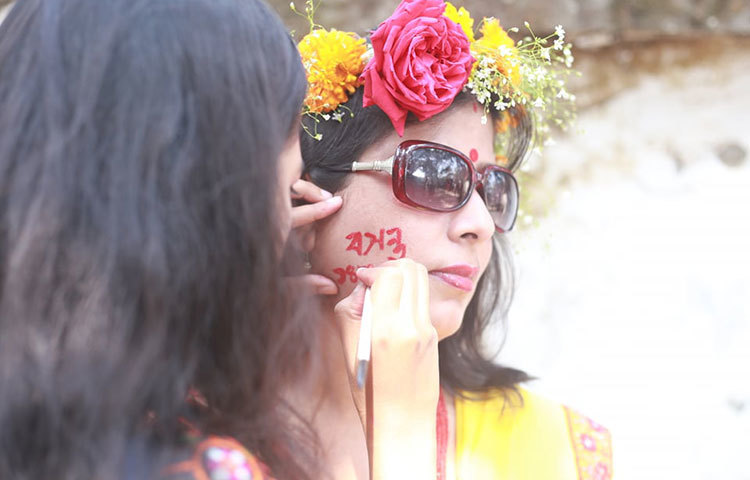 গালে বসন্তের আলপনা আঁকছেন এক তরুণী। ছবি: মাহবুব আলম