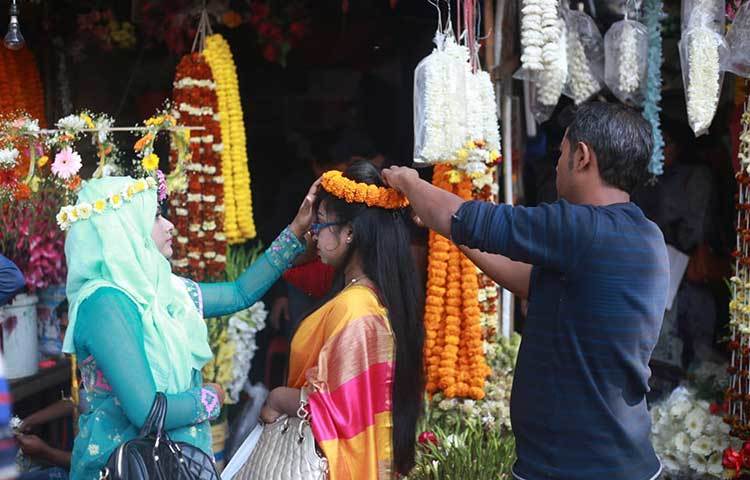 একটি ফুলের দোকানে গাঁদা ফুল দিয়ে সাজছেন এক তরুণী। ছবি: মাহবুব আলম