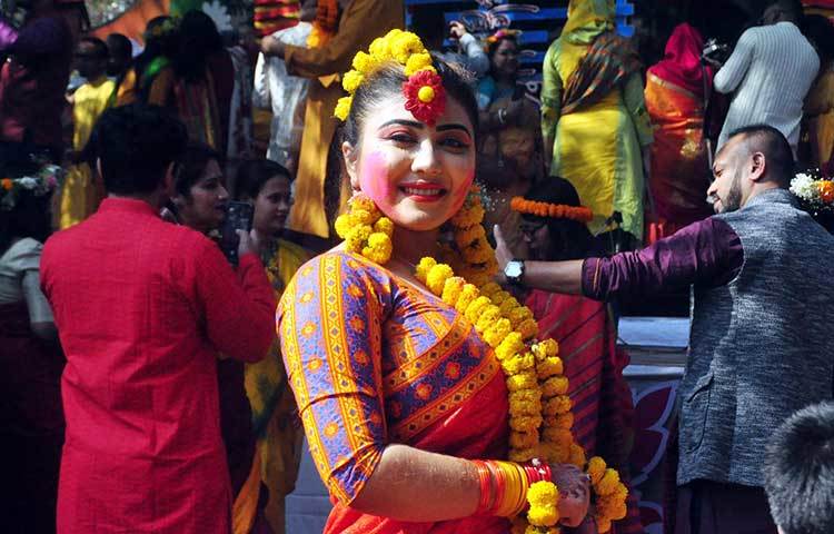 লাল শাড়িতে গাঁদা ফুল গলায় দিয়ে বাসন্তি সাজে সেজেছেন এক তরুণী। ছবি: বিপ্লব দিক্ষিৎ