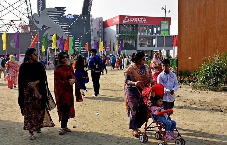 শিশুসন্তানকে নিয়ে বাণিজ্য মেলার মাঠে ঘুরছেন এক মা। ছবি : বিপ্লব দিক্ষিৎ