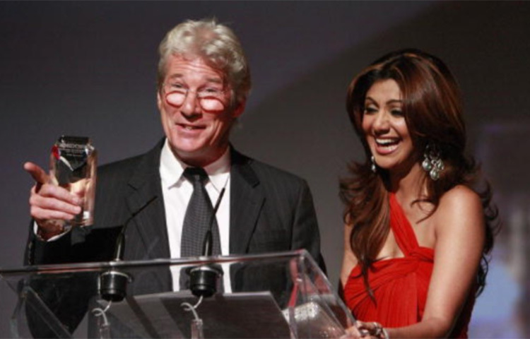 ২০০৭ সালে শিল্পা এইডস নিয়ে একটি সচেতনতামূলক প্রচারে যোগ দিয়েছিলেন। আমেরিকার অভিনেতা রিচার্ড গেরেও তাতে হাজির ছিলেন। মঞ্চে উঠেই সবাইকে অবাক করে শিল্পাকে জড়িয়ে ধরে ক্রমাগত চুমু খেতে শুরু করেন তিনি। ছবি: সংগৃহীত