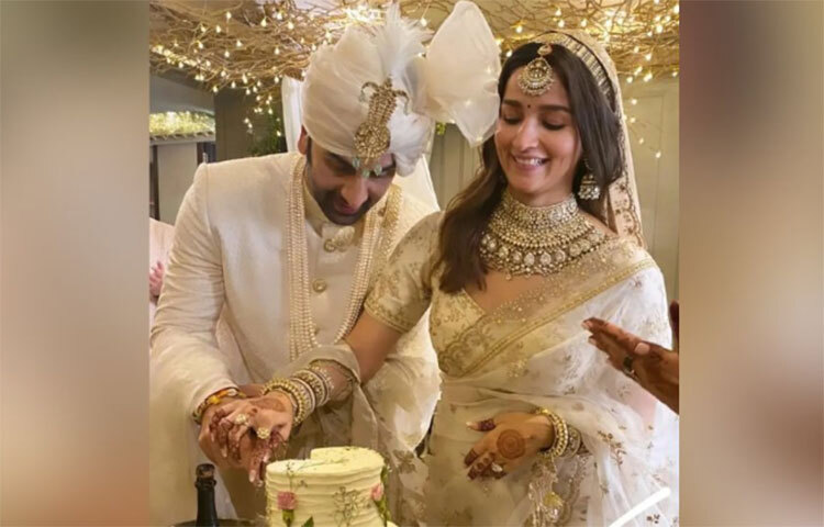 রীতি মেনে বাহারি ভোজের আগে বর-বউয়ের সামনে দুধ সাদা কেক। গায়ে গোলাপি রঙের বসরাই গোলাপ আঁকা। হাসতে হাসতে তুলতুলে নরম কেকের বুকে মেহেদি রাঙা হাতে ছুরি বসিয়েছেন আলিয়া! ছবি: সংগৃহীত