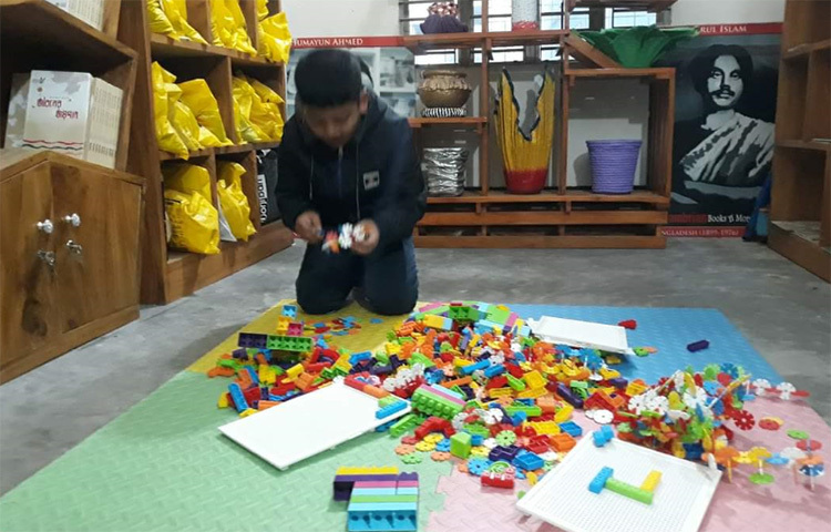 সেখানে জ্ঞানের ভান্ডার সমৃদ্ধ করতে স্থানীয় স্কুল-কলেজের শিক্ষার্থীসহ বিভিন্ন বয়সী পাঠকের সমাবেশ। এ যেন একখণ্ড জ্ঞান অর্জনের তীর্থভূমি। ভেদরগঞ্জ বাজারের সড়কের পাশ ঘেঁষে তিন তলা ভবনটির ছাদে উঠলেই যে কারও নজরকাড়বে বাহারি গাছ। দেয়ালগুলো ঢাকা নানা রঙে। আছে প্লাস্টিকের কাটা বোতল রঙ দিয়ে সাজানো গাছের টব। সুন্দর বসার ব্যবস্থার পাশাপাশি আছে ছবি তোলার স্থানও। ছবি: মো. ছগির হোসেন