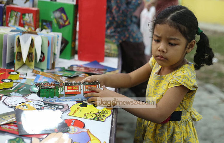 শিশুটির মুখ দেখে মনে হচ্ছে কোন বইটি কিনবে তার সিদ্ধান্ত নিতে পারছে না। ছবি: মাহবুব আলম