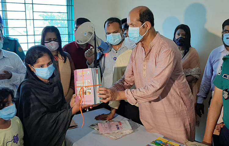 আগুনে পাঠ্যবই পুড়ে যাওয়া সপ্তম শ্রেণির ছাত্রী ফাতেমা আক্তার স্মৃতিকে নতুন পাঠ্যবই উপহার দিয়েছেন ঢাকা উত্তর সিটি করপোরেশনের মেয়র আতিকুল ইসলাম। ছবি: জাগো নিউজ