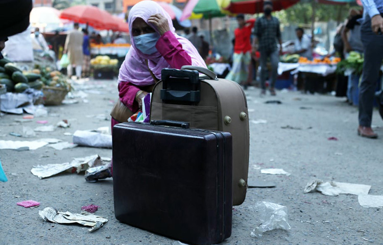 রাজধানী থেকে বাড়ি ফিরতে চাওয়া এই নারী গাড়ি না পেয়ে হতাশ হয়ে রাস্তা বসে আছেন। ছবি: জাগো নিউজ