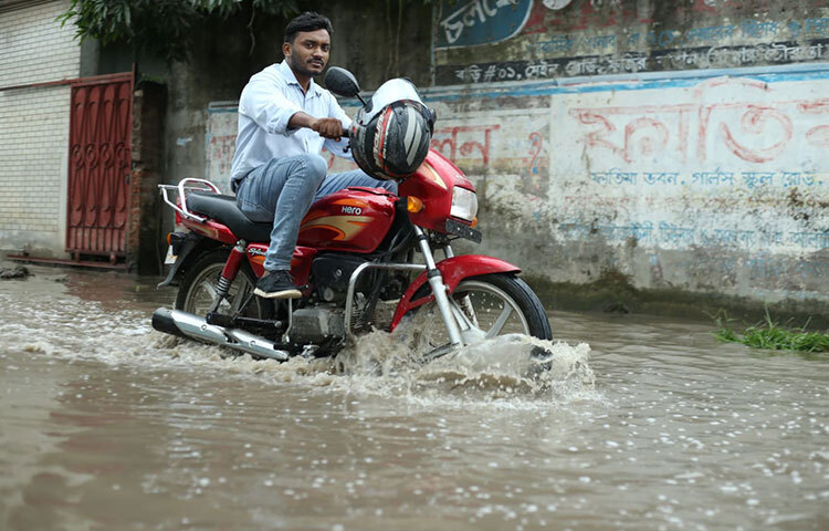 মোটরসাইকেল নিয়ে বৃষ্টিতে জমে থাকা পানিতে আটকে পড়েছেন তিনি। ছবি: মাহবুব আলম