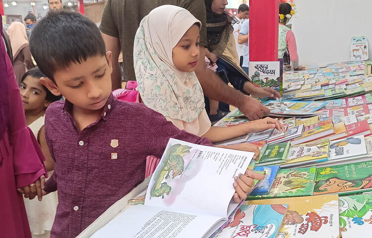অমর একুশে বইমেলায় খুদে পাঠকরা তাদের পছন্দের বই বাছাই করছে। ছবি: মাহবুব আলম