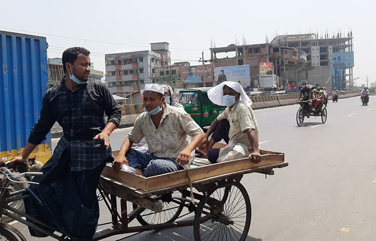 লকডাউনের মধ্যে গণপরিবহন না থাকায় ভ্যান গাড়িতে করে গন্তব্যে যাচ্ছেন নিন্ম আয়ের মানুষ। ছবি: বিপ্লব দিক্ষিৎ