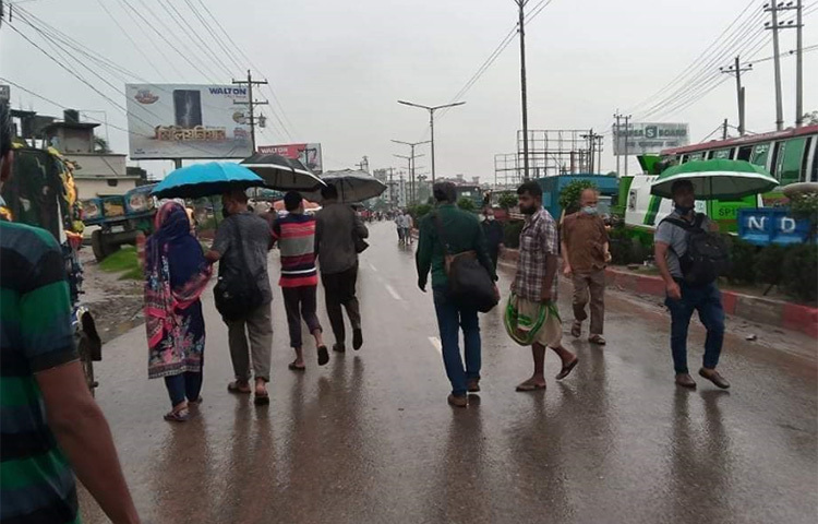 কর্দমাক্ত পথে হেঁটে, বৃষ্টিতে ভিজে, চরম দুর্ভোগ সঙ্গী করে দীর্ঘ কয়েক কিলোমিটার পথ পেরিয়ে রাজধানীতে যাচ্ছেন হাজারো মানুষ। এদের বেশিরভাগই যাচ্ছেন কর্মস্থলে। ছবি: জাগো নিউজ