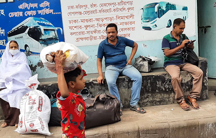 রাজধানীতে এসে গন্তব্যে যাওয়ার জন্য গাড়ির অপেক্ষায় বসে আসেন গ্রাম থেকে আসা এই যাত্রীরা। ছবি: বিপ্লব দিক্ষিৎ