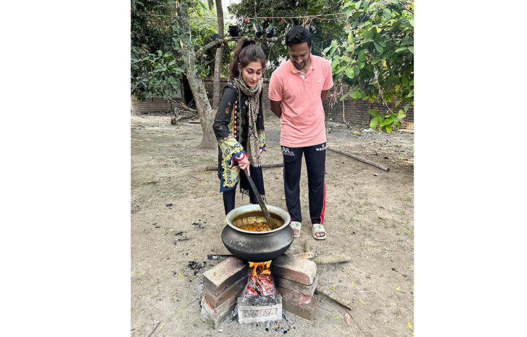 বিশ্ববিখ্যাত অলরাউন্ডার ক্রিকেটার সাকিব আল হাসান। তার কয়েকটি ছবি ভাইরাল হয়েছে। ছবিতে দেখা গেছে, বাড়ির আঙিনায় তৈরি অস্থায়ী চুলায় হাঁড়িতে রান্না করছেন তিনি। তাতে লাকড়ি দিয়ে আগুন ধরানোর চেষ্টা করছেন সাকিব। আরেকটি ছবিতে দেখা যায়, গরুর মাংস রান্না করছেন সাকিব আল হাসানের স্ত্রী শিশির। তার পাশে দাঁড়িয়ে আছেন সাকিব। ছবি: ফেসবুক