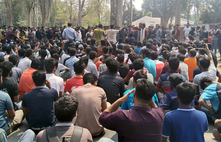 স্থানীয়দের সঙ্গে সংঘর্ষের জেরে পুলিশের গুলিতে শিক্ষার্থী আহতের ঘটনায় রাজশাহী বিশ্ববিদ্যালয় প্রশাসনের পদক্ষেপের গাফিলতির অভিযোগ তুলে উপাচার্য অধ্যাপক ড. গোলাম সাব্বির সাত্তারকে ঘিরে রেখেছেন বিক্ষোভরত শিক্ষার্থীরা। আজ দুপুর ১২টার দিকে উপাচার্যকে শহীদ তাজউদ্দীন আহমদ সিনেট ভবনের পশ্চিমকোণে তাকে ঘিরে ধরেন শিক্ষার্থীরা। ছবি: জাগো নিউজ