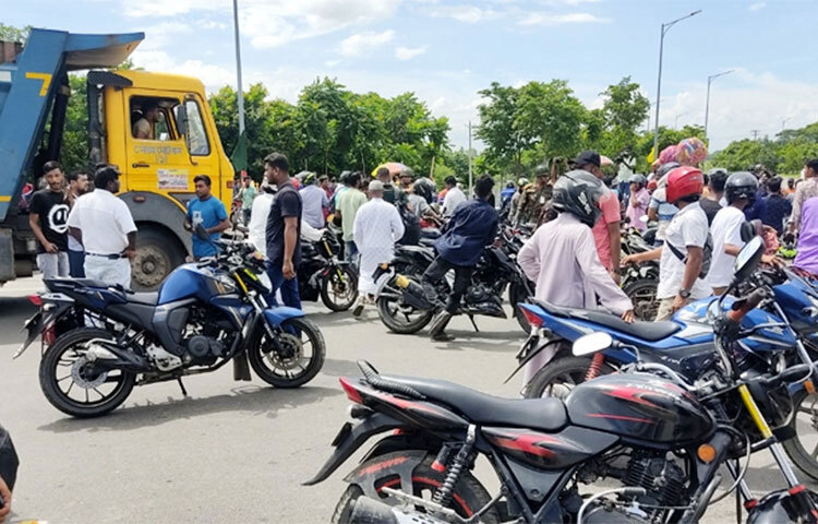 পদ্মা সেতুর জাজিরা প্রান্তের টোল প্লাজার সামনে মোটরসাইকেল সড়কের ওপর রেখে বাস, ট্রাক ও প্রাইভেটকার চলাচলে বাধা দিয়েছেন বাইকাররা। আজ দুপুর ১টা ৫০ মিনিট থেকে ২টা ১০ মিনিট পর্যন্ত তারা সড়ক অবরোধ করেন। ছবি: জাগো নিউজ