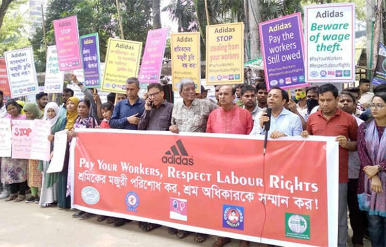 আন্তর্জাতিক ব্র্যান্ড এডিডাসের আট কারখানার শ্রমিক-কর্মচারীদের মজুরি পরিশোধে মানববন্ধন হয়েছে। এই কারখানাগুলো কম্বোডিয়ায় অবস্থিত। ১১ দশমিক ৭ মিলিয়ন মার্কিন ডলার মজুরি পরিশোধের দাবি জানানো হয়। আজ জাতীয় প্রেস ক্লাবের সামনে মানববন্ধনে অংশগ্রহণ করেন পাঁচ শ্রমিক সংগঠনের নেতাকর্মী ও শ্রমিকেরা। ছবি: বিপ্লব দিক্ষিৎ
