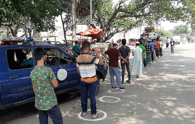আজ দুপুরে রাজধানীর নিউমার্কেটের কাছে ক্রেতারা স্বাস্থ্যবিধি মেনে টিসিবির পণ্য কিনছেন। ছবি: বিপ্লব দিক্ষিৎ