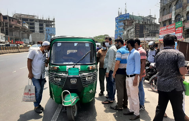 একটি মাত্র সিএনজি, এটিকে ভাড়া নেয়ায় জন্য অনেক মানুষের চেষ্টা। লকডাউনের মধ্যে গাড়ি কম থাকায় এমন দৃশ্য রাজধানীর বিভিন্ন সড়কে দেখা যায়। ছবি: বিপ্লব দিক্ষিৎ