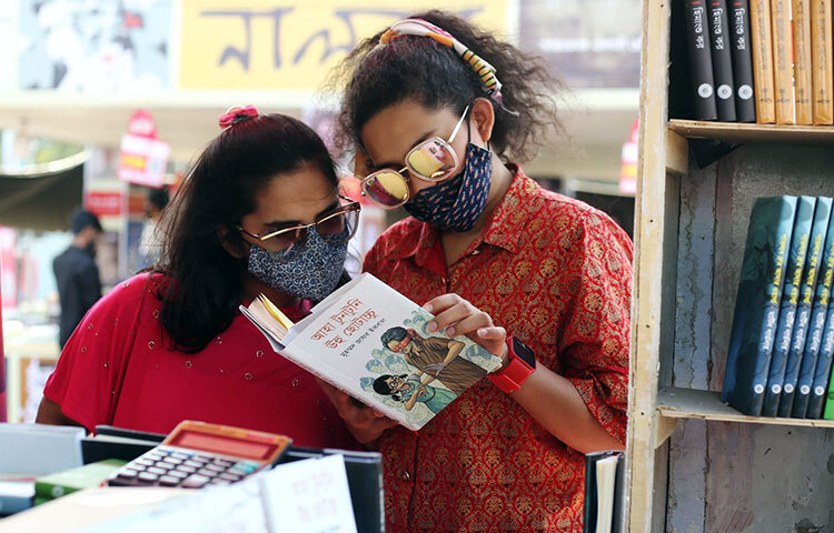 একটি স্টলে প্রিয় লেখকের বই গভীর মনোযোগে দেখছেন দুই পাঠক। ছবি: মাহববু আলম
