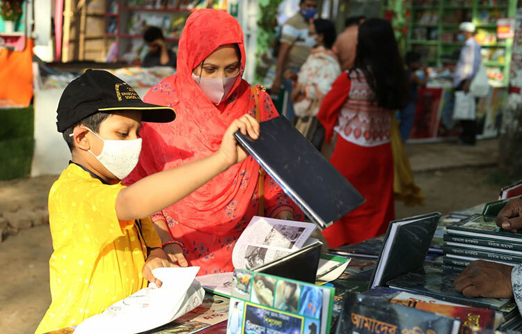 সন্তানকে বইয়ের সঙ্গে পরিচয় করিয়ে দিতে এই মা অমর একুশে বইমেলায় এসেছেন। ছবি: মাহবুব আলম