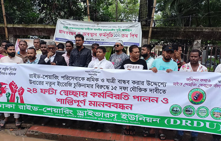 সর্বনিম্ন ১০০ টাকা ভাড়া নির্ধারণ, চালকদের নিরাপত্তার দায়িত্ব নেওয়া, ট্যাক্স মওকুফ ও ঝুঁকিবিমাসহ ১৫ দফা দাবিতে ২৪ ঘণ্টার কর্মবিরতি পালন ও মানববন্ধন করেছে ঢাকা রাইড-শেয়ারিং ড্রাইভার্স ইউনিয়ন (ডিআরডিইউ)। আজ জাতীয় প্রেস ক্লাবের সামনে কর্মবিরতি পালন ও মানববন্ধনে তারা এসব দাবি জানান। ছবি: জাগো নিউজ