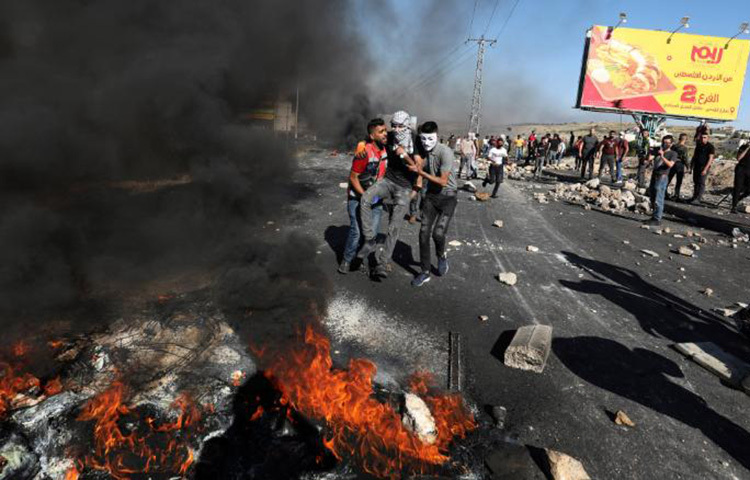 ইসরাইলি হামলায় ফিলিস্তিনি এক বিক্ষোভকারী আহত হয়েছেন। তাকে নিয়ে যাচ্ছেন তার সহযোদ্ধারা। ছবি: সিএনএন