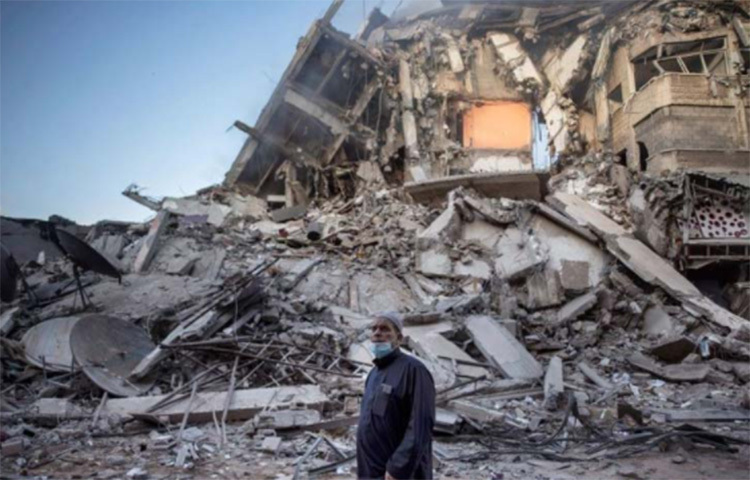 গাজা শহরে ইসরায়েলি বিমান হামলায় ধ্বংসস্তূপে পরিণত একটি ভবন। সেই ধ্বংসস্তূপে দাঁড়িয়ে আছেন একজন ফিলিস্তিনি। ছবি: এপি