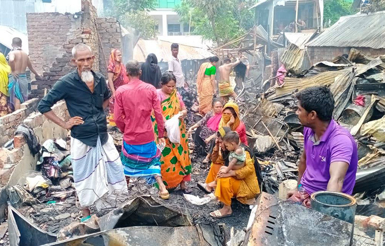 পুড়ে যাওয়া বসতভিটার মাঝে দাঁড়িয়ে আছেন বস্তিবাসী। ছবি: জাগো নিউজ
