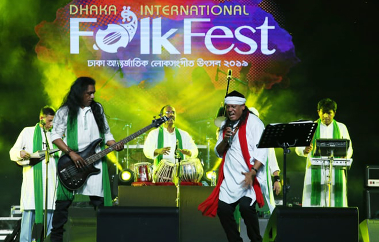 মাথায় সাদা পাগড়ি, সাদা পাঞ্জাবি, কাঁধে ঝোলানো লাল রঙের গামছা। ফোকফেস্টের মঞ্চে আসলেন ফোক গানের জনপ্রিয় শিল্পী ফকির শাহাবুদ্দীন। তাকে দেখেই উচ্ছ্বাস প্রকাশ করলেন দর্শকরা। ছবি: মাহবুব আলম