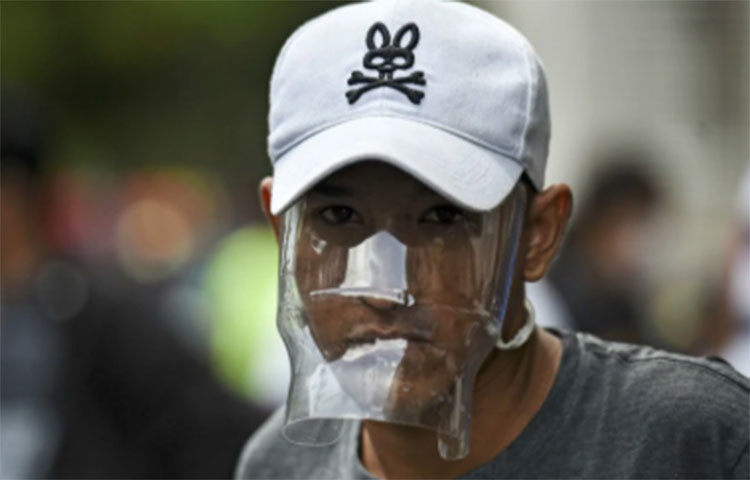 ভেনিজুয়েলার এক পরিযায়ী শ্রমিক এভাবেই পানির বোতল কেটে মাস্ক বানিয়েছেন। ছবি: এএফপি