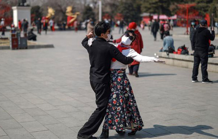 যে কোনো ভাইরাসের বিস্তার ঠেকাতে কয়েক বছর ধরেই চীনারা মাস্ক পরছেন। করোনার আঘাত শুরুর প্রথম দিকেই মাস্ক পরা বাধ্যতামূলক করা হয়েছিল। ছবিতে শেনইয়াংয়ের মাস্ক পরা এক দম্পতিকে বসন্তের রোদে নাচতে দেখা যাচ্ছে।